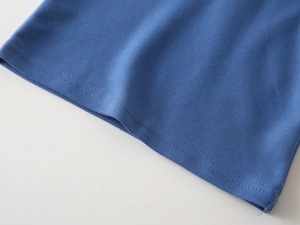 Close-up of blue piqué cotton polo shirt hem with high-quality double-needle stitching