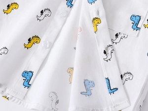 Detailed macro view of white cotton shirt featuring colorful cartoon dinosaur prints