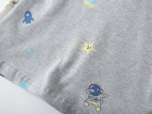 Close-up of soft grey cotton fabric with cartoon astronaut and rocket print for kids