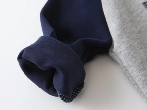 Detailed macro view of the ribbed navy blue cuffs and thick grey heather knit fabric