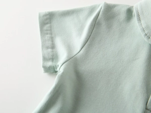 Dettaglio della polo verde menta con cuciture lisce e trama del cotone lavorato a maglia