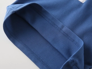 Detailed macro view of the blue cotton polo shirt hem showing double-stitched sewing