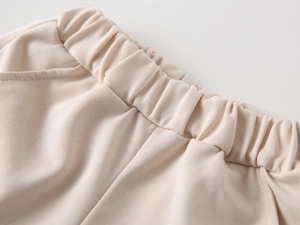 Close-up of elastic waistband on beige ribbed knit trousers for toddler boys