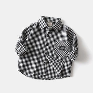Detail of boys' black and white gingham shirt featuring a front pocket and fashion label