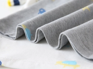 Close-up of soft cotton knit fabric with blue stars and yellow cartoon prints on kids' polo