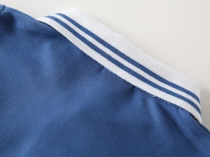Detailed view of kids blue polo shirt with white striped collar and mesh fabric texture