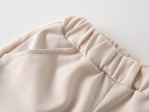 Detail of elastic waistband and reinforced side pockets on beige knitted cotton shorts