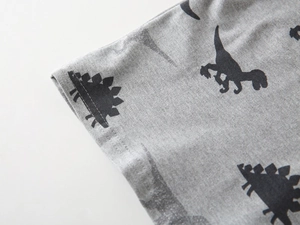 Close-up of grey cotton polo shirt fabric with detailed black dinosaur print patterns