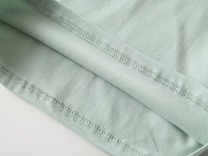 Dettaglio dell'orlo a doppia cucitura sulla polo in maglia di cotone verde menta
