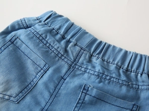 Detail of light blue kids denim shorts showing elastic waistband and reinforced stitching