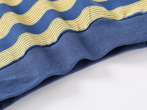 Macro shot of navy knit sweater hem with yellow wavy stripes and ribbed elastic texture