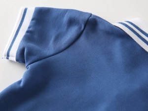 Detail of navy pique polo shirt showing breathable mesh fabric and striped ribbed cuff