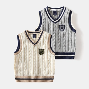Detail of knit child sweater vest with V-neck, nautical stripes, and shield embroidery