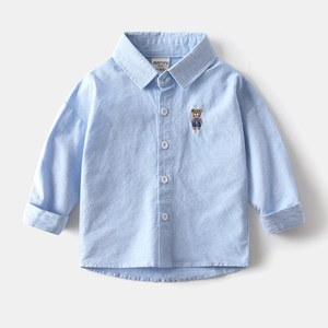 Détail de la chemise oxford bleu clair avec broderie ours et boutons blancs garçons