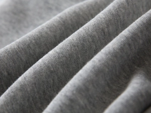Close-up of soft grey knitted cotton blend fabric showing breathable texture and fibers