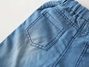 Detail shot of light blue washed denim shorts showing elastic waist and back pocket