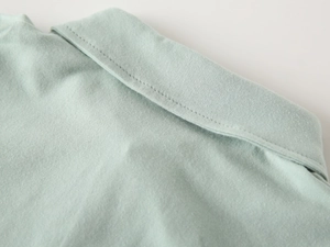 Dettaglio macro del colletto della polo verde menta con cuciture rifinite e trama in cotone