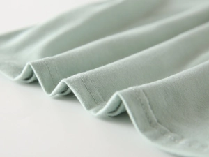Dettaglio della doppia cucitura sull'orlo di una polo in maglia di cotone verde chiaro