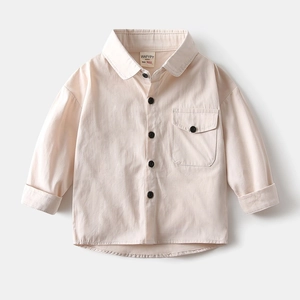 Détail d'une chemise en coton beige pour garçons avec poche et boutons noirs contrastés