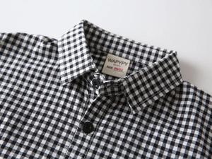 Close-up of the brand label and collar detail on a black and white checkered kids shirt
