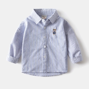 Détail d'une chemise Oxford pour garçons à rayures bleues et blanches avec écusson d'ours