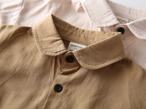 Détail des chemises en coton à manches longues montrant les cols ronds et la texture