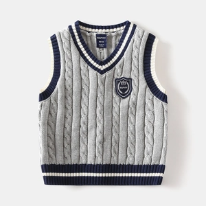 Macro detail of kids knit vest showing textured cable knit fabric and embroidered chest badge
