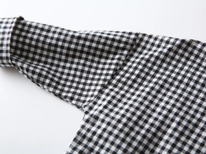 Detail view of neatly stitched cuffs on a black and white gingham checkered cotton shirt