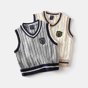 Detail of cable knit vests for kids with v-neck contrast stripes and crest badge