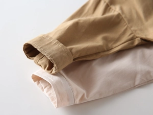 Détail de poignets en coton haute densité en kaki et blanc cassé, coutures fines