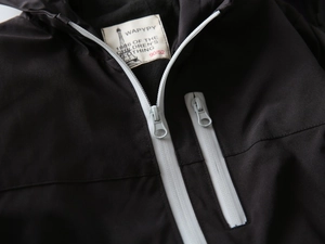 Detail shot of black hooded kids jacket showing white zipper and soft fleece lining