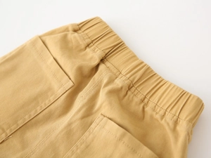 Detail of yellow cargo pants showing elastic waistband and high-density cotton twill fabric
