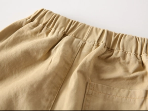 Detail of khaki cotton twill pants featuring an elastic waistband and rear pocket stitching