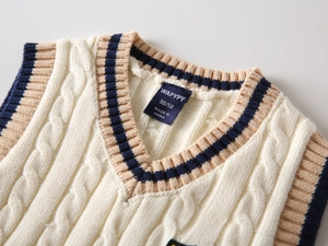 Detailed view of kids cable knit sweater vest with contrast V-neck and interior brand label