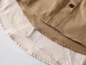 Détail d'une chemise kaki pour garçon avec ourlet superposé et boutons noirs design