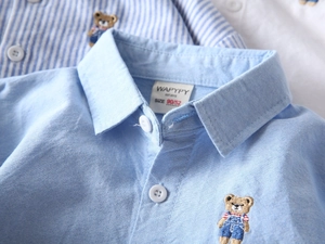 Détail du col d'une chemise Oxford bleue avec broderie ours et texture de tissu premium