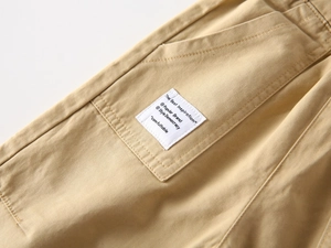 Detailed view of khaki cotton cargo pants with side pocket and square textile label