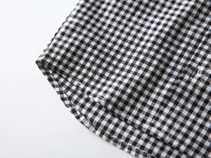Detail of boys' gingham shirt curved hem with premium double stitching on white background