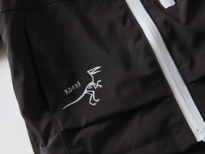 Close-up of black windproof jacket with white dinosaur skeleton print and zipper detail