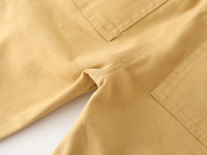Macro detail of yellow cargo pants showing durable cotton twill fabric and reinforced seams