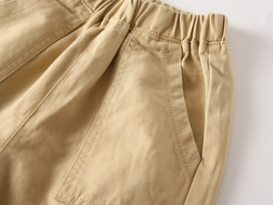 Detail of khaki cotton twill pants featuring an elastic waistband and side pocket stitching