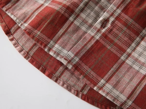 Close-up of red plaid shirt rounded hem with high-quality stitching and cotton-linen texture