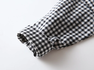 Macro shot of black and white gingham shirt cuff showing breathable cotton texture