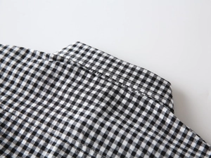 Detailed close-up of the black and white gingham collar on a boy's cotton button-down shirt