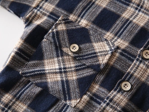 Detail of classic flannel plaid shirt featuring a chest pocket and branded button engraving