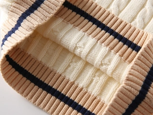 Detail of cable knit pattern and contrast striped cuffs on kids beige vest sweater