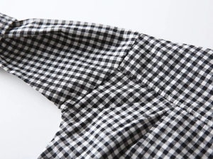 Close-up of black and white gingham shirt fabric showing premium stitching and cotton texture