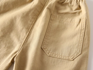 Detailed close-up of khaki cotton twill fabric with back pocket stitching on kids' pants