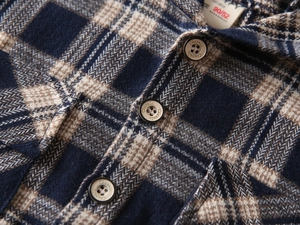 Detailed close-up of flannel plaid shirt fabric with Classic button and size tag