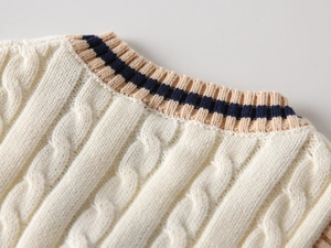 Detailed macro view of cable knit texture and striped ribbed collar on kids' vest